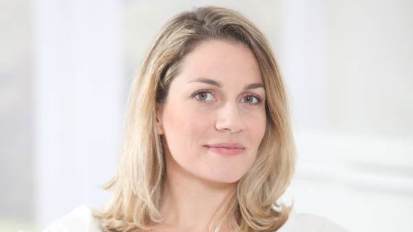 Portrait of blond woman in her 30s sitting on sofa